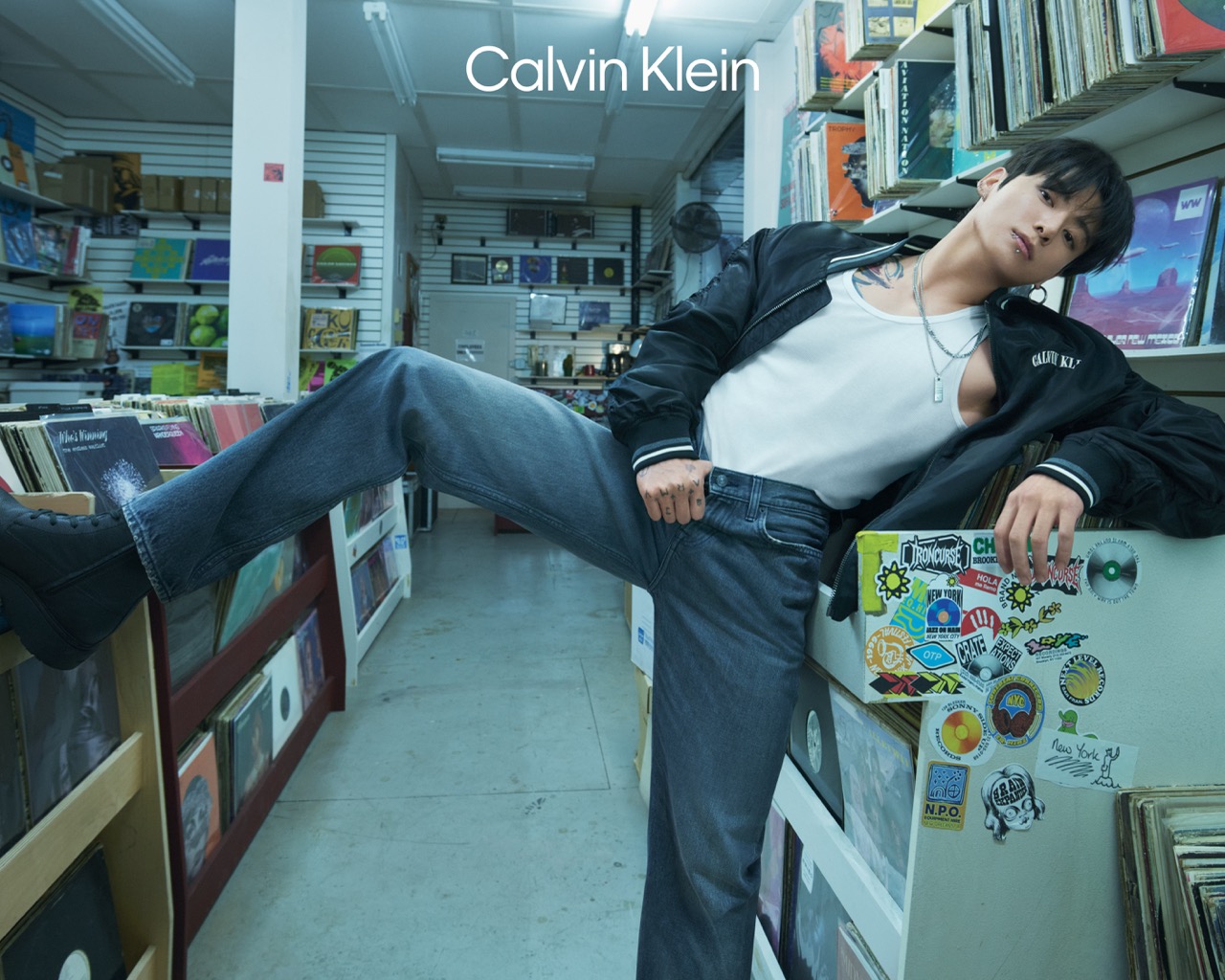 Jungkook in a record store wearing Calvin Klein bomber jacket and denim for the Spring 2026 campaign