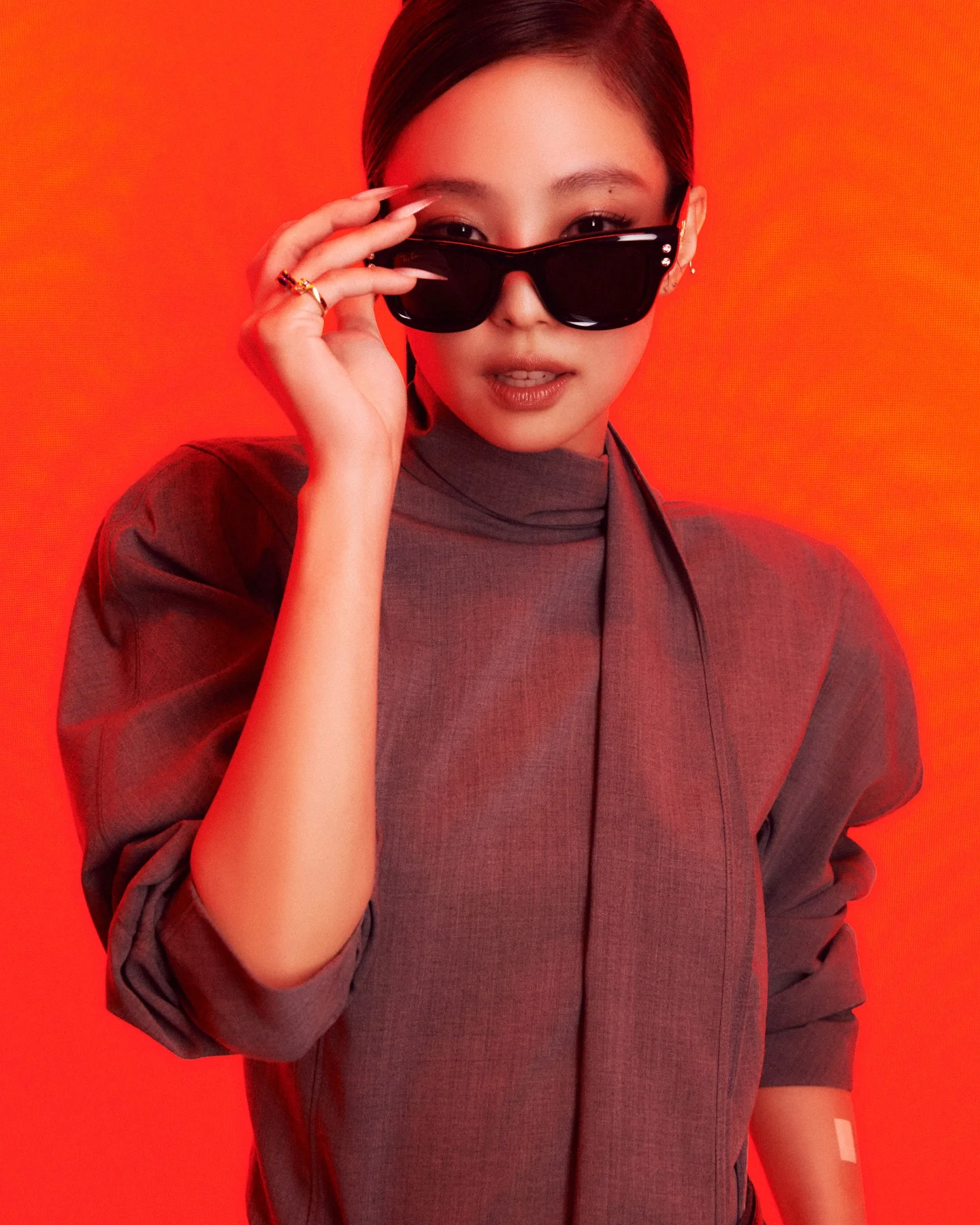 Jennie wearing black Ray-Ban sunglasses in an official monochrome campaign portrait.