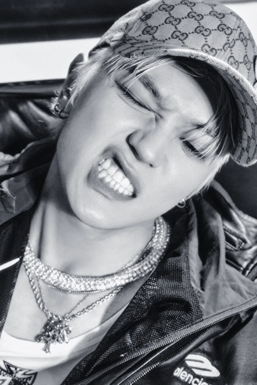 Black-and-white teaser portrait of Taeyong wearing a patterned cap and layered chains for Rock Solid