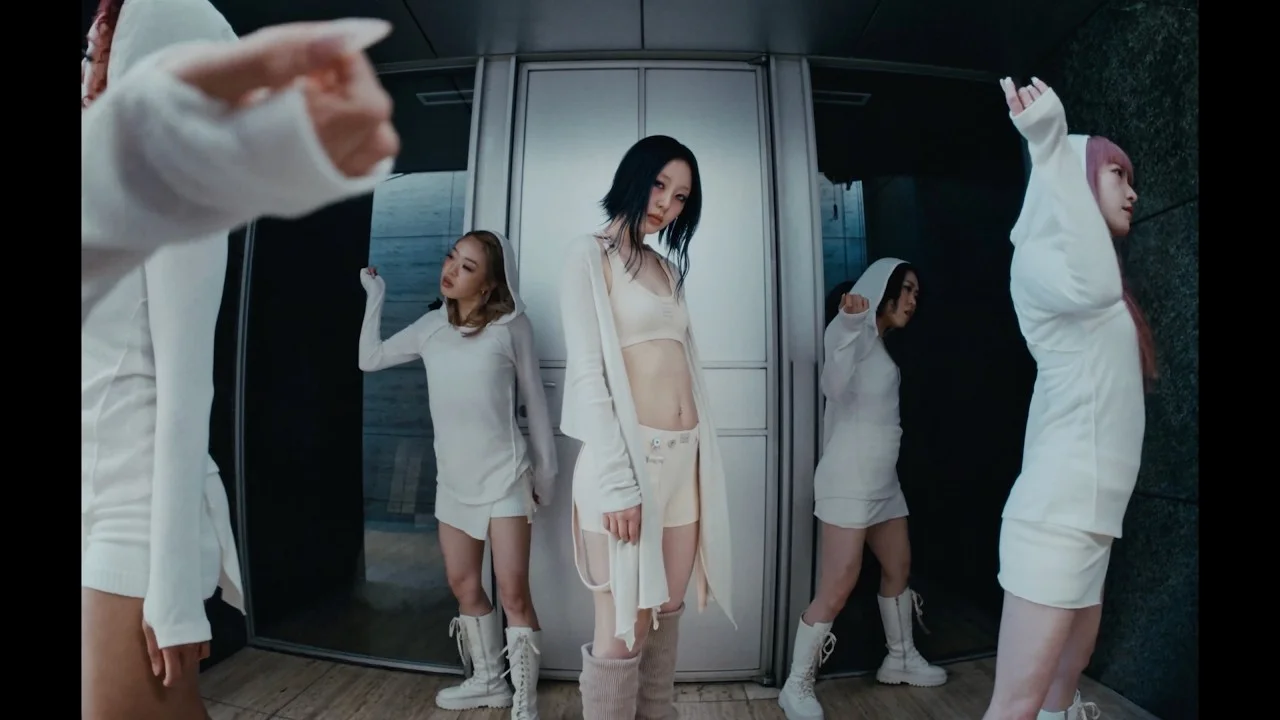 Yves stands at the center of a group performance shot from the NAIL teaser imagery.