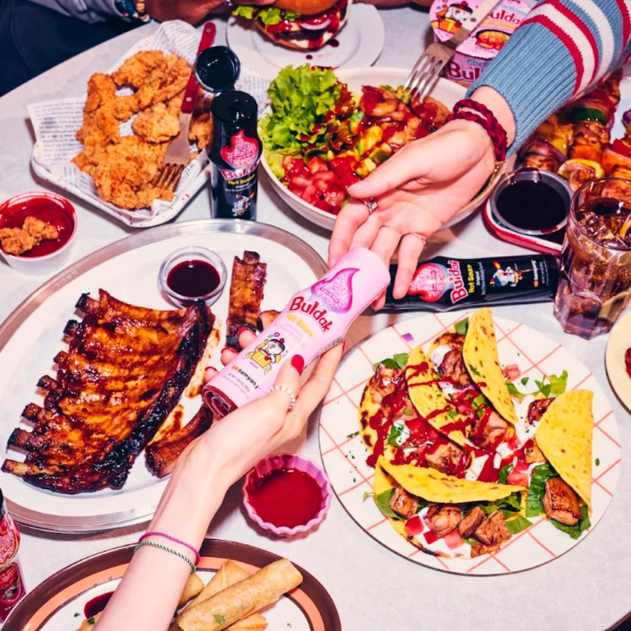 Buldak sauce bottles held over a table filled with festival food at Coachella 2026