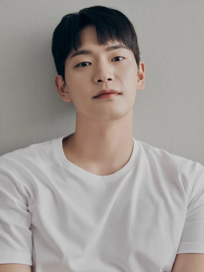 Portrait of actor Kang Sang Jun in a white T-shirt against a neutral wall