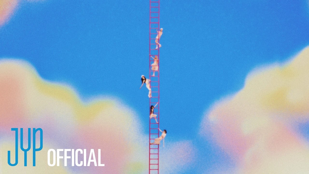 Members of ITZY appear on a ladder in the official Motto trailer still against a bright cloud-filled sky.