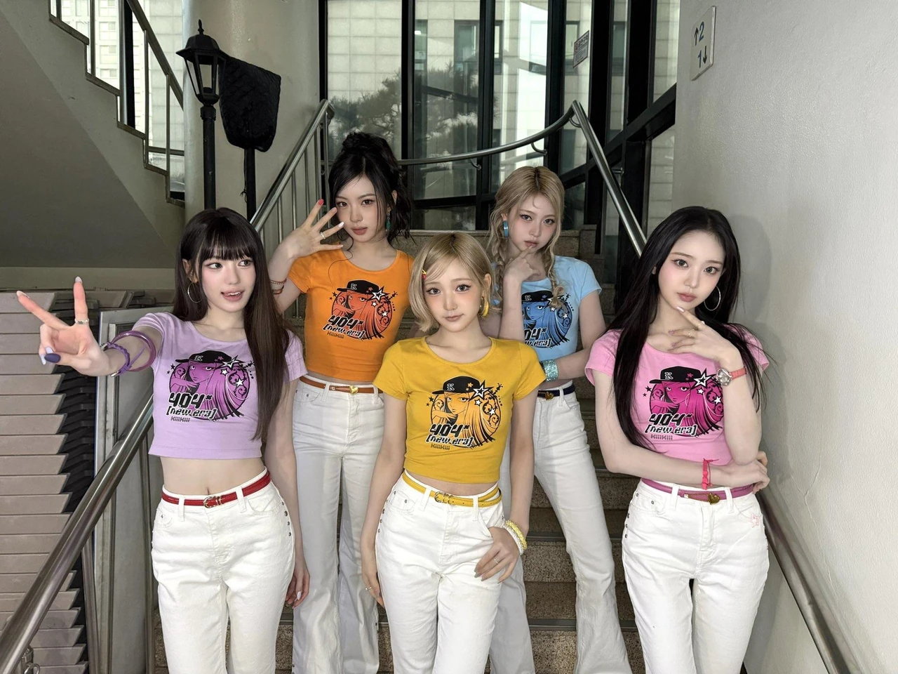 Members of KiiiKiii pose during local music show promotions for 404 (New Era) in matching colorful tops and white pants.