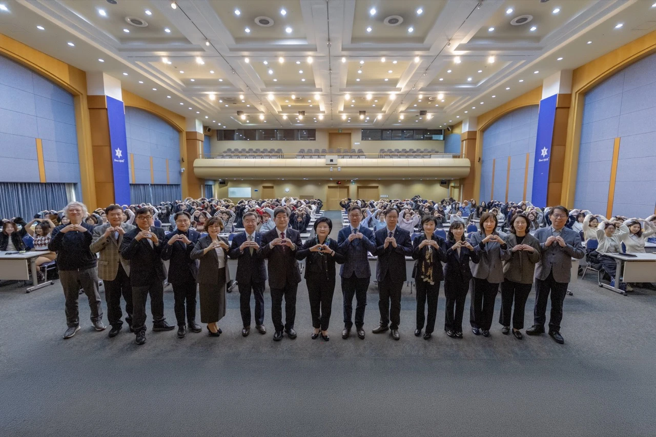 Faculty, staff, and students make heart gestures during Hallyu International College orientation at Sookmyung Women’s University