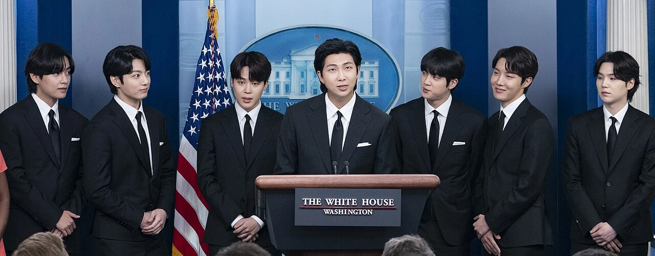 BTS speaking at the White House press briefing room in black suits