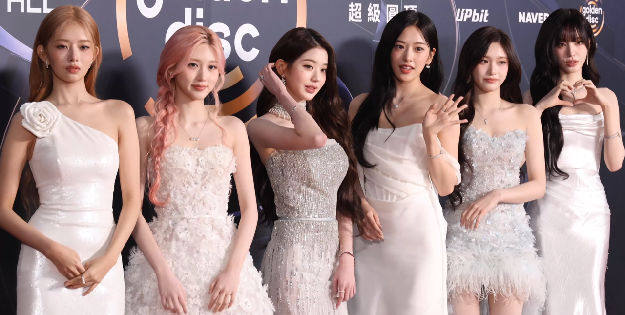IVE posing together on a red carpet in coordinated white gowns